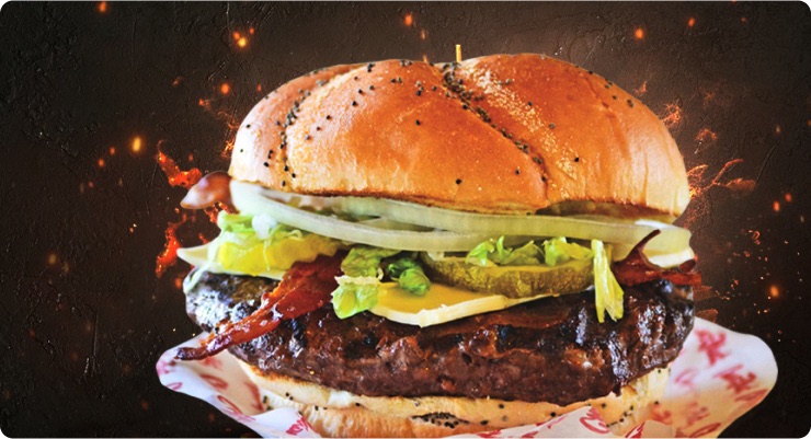 Charbroiled bacon burger with onions and pickles on a poppy seed kaiser roll
